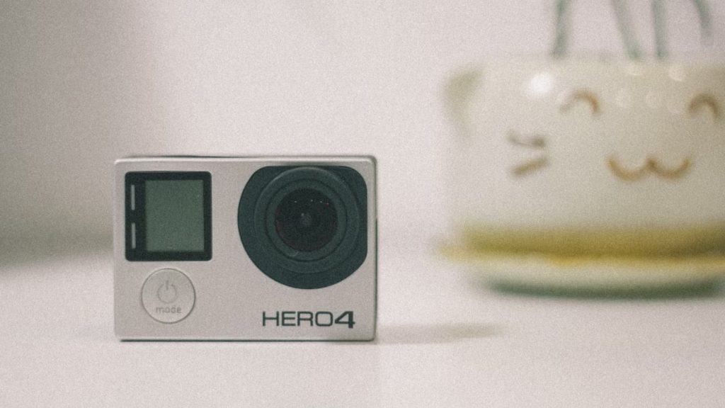 A GoPro Hero 4 action camera on a desk with soft lighting, suitable for technology themes.